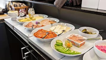 Un bufé con diversos alimentos, incluyendo carnes en rodajas, quesos y verduras.