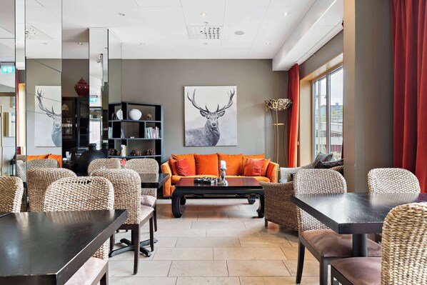 A modern living room with a sofa, chairs, a coffee table, and a bookshelf.