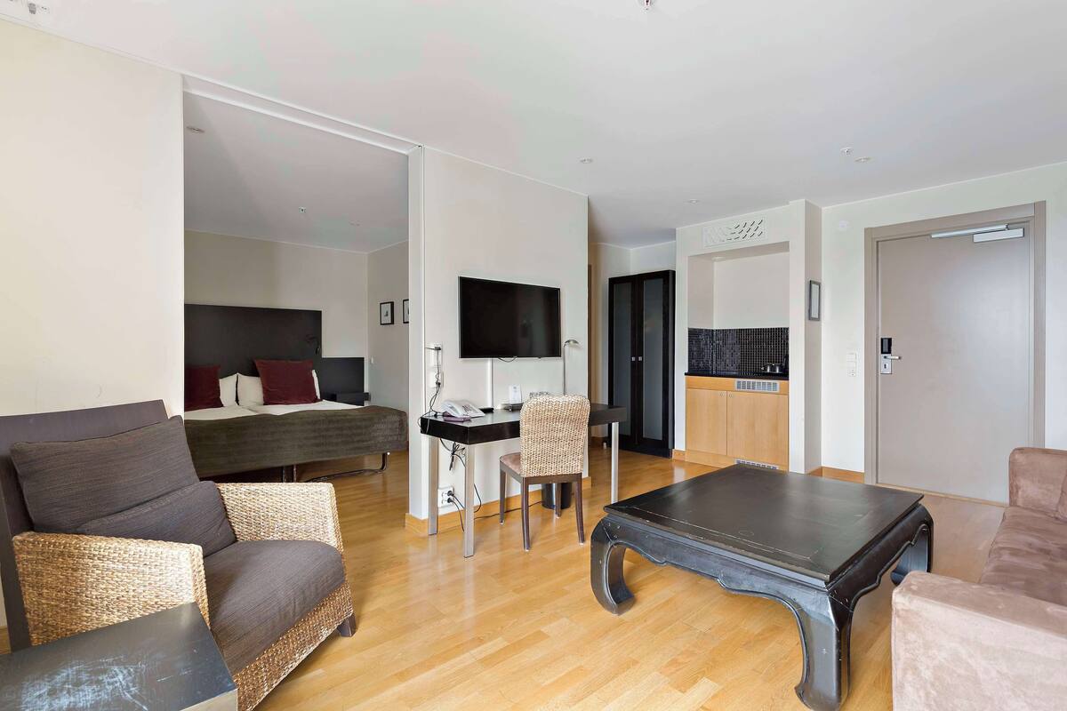 A modern living room with a sofa, a coffee table, and a dining area with a chair and table.