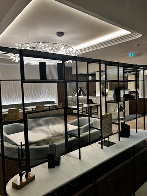 A modern interior with a sectional sofa, a dining area, and a decorative light fixture. - Hôtel Le Mathurin (Paris)