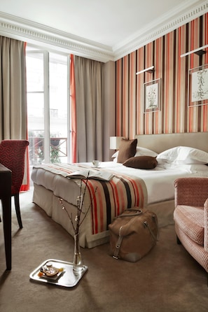 A hotel room with a bed, a chair, a suitcase, and a tray with food. - Hôtel Le Mathurin (Paris)