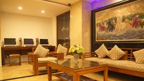 A hotel lobby with a sofa set, a coffee table, and a desk with computers. - Golden Beach Nha Trang Boutique Hotel (Nha Trang)