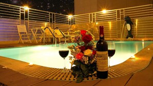 A poolside area with lounge chairs, a bottle of wine, and a glass of wine on a table. - Golden Beach Nha Trang Boutique Hotel (Nha Trang)