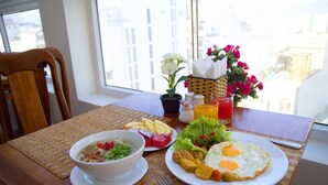 A dining table with a meal consisting of soup, fruit, fried eggs, and vegetables. - Golden Beach Nha Trang Boutique Hotel (Nha Trang)