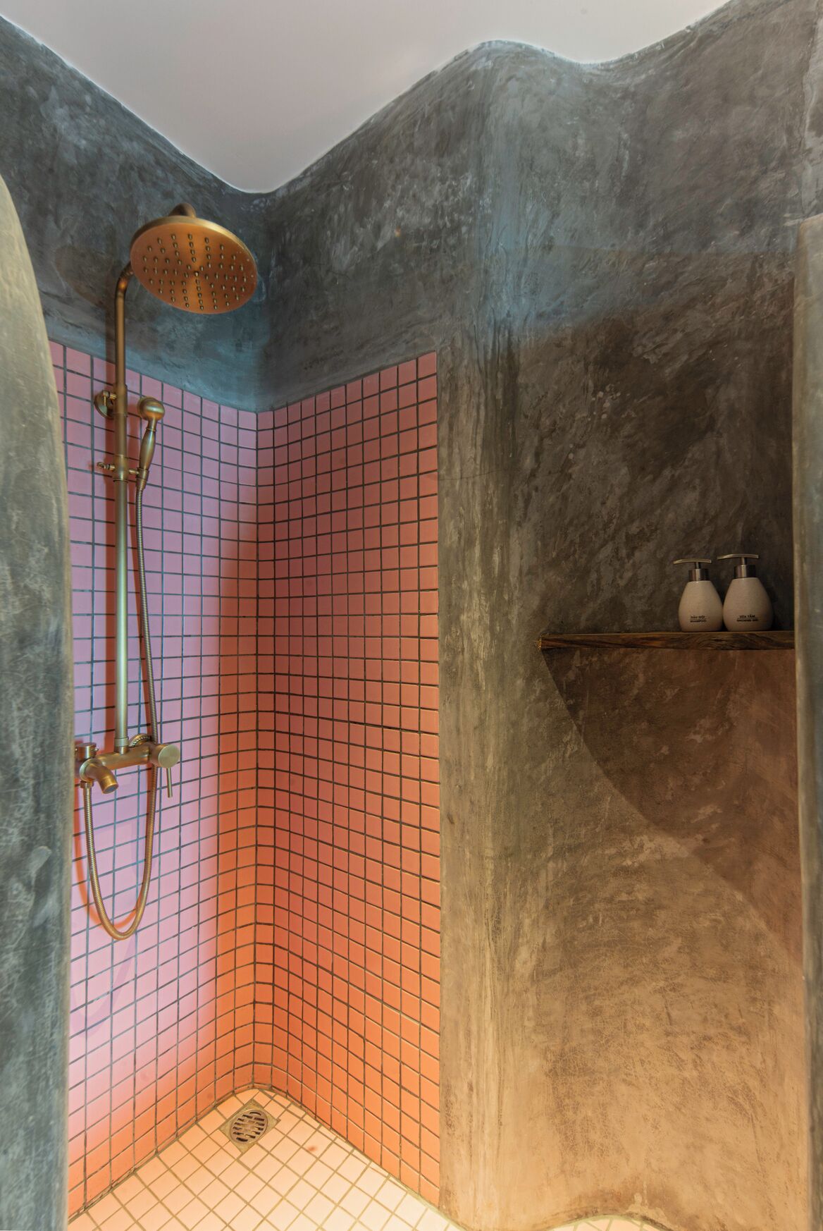 A shower with a handheld showerhead, a wall-mounted faucet, and a tiled floor.