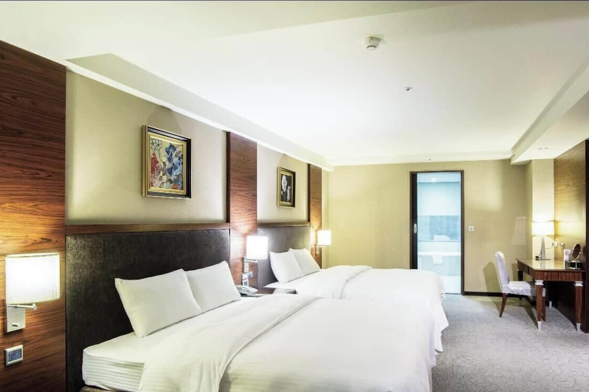Une chambre d’hôtel avec un grand lit, des lampes de chevet, un bureau et un téléviseur.