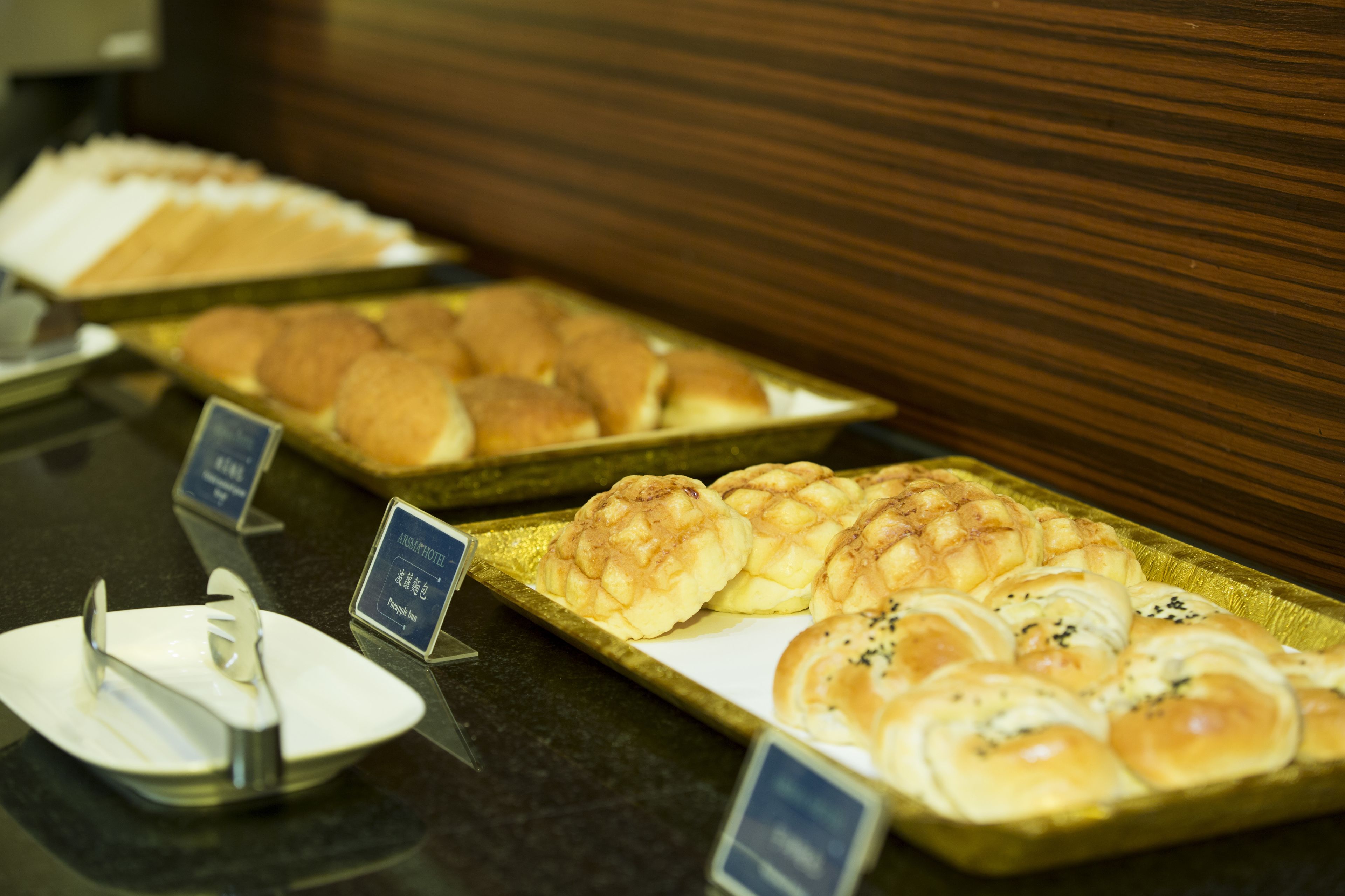 A buffet with various baked goods, including rolls and pastries, arranged on trays.