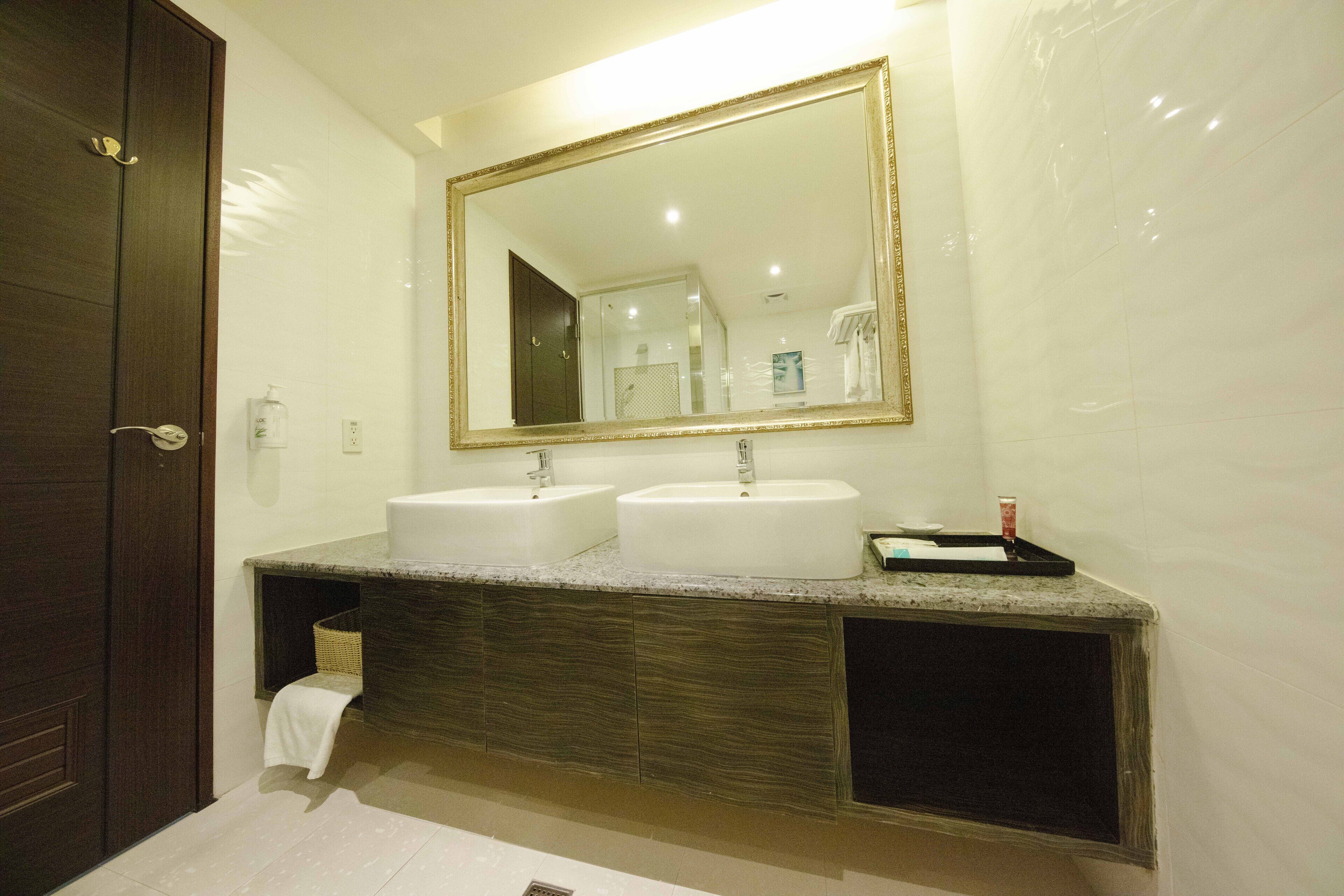 A bathroom with two sinks, a large mirror, and a dark wooden door.