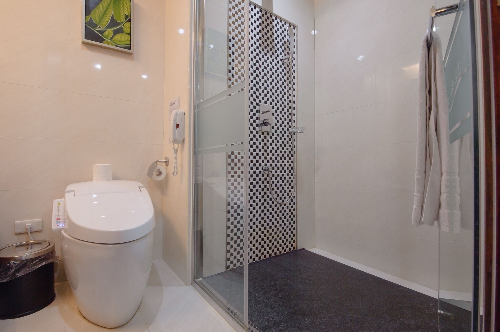 A modern bathroom with a toilet, a glass-enclosed shower with a checkered pattern, and a towel rack.