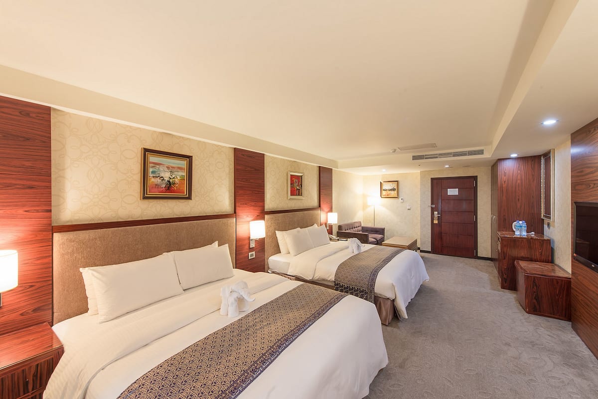 Une chambre d’hôtel avec deux lits, un bureau, une chaise, une télévision et une armoire.