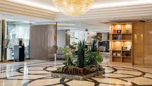 A lobby with a large chandelier, a reception desk, and a plant area. - Arsma Hotel (Hualien City)