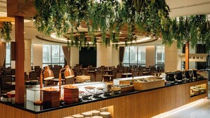 A modern hotel lobby with a central buffet area, seating arrangements, and hanging greenery. - Arsma Hotel (Hualien City)