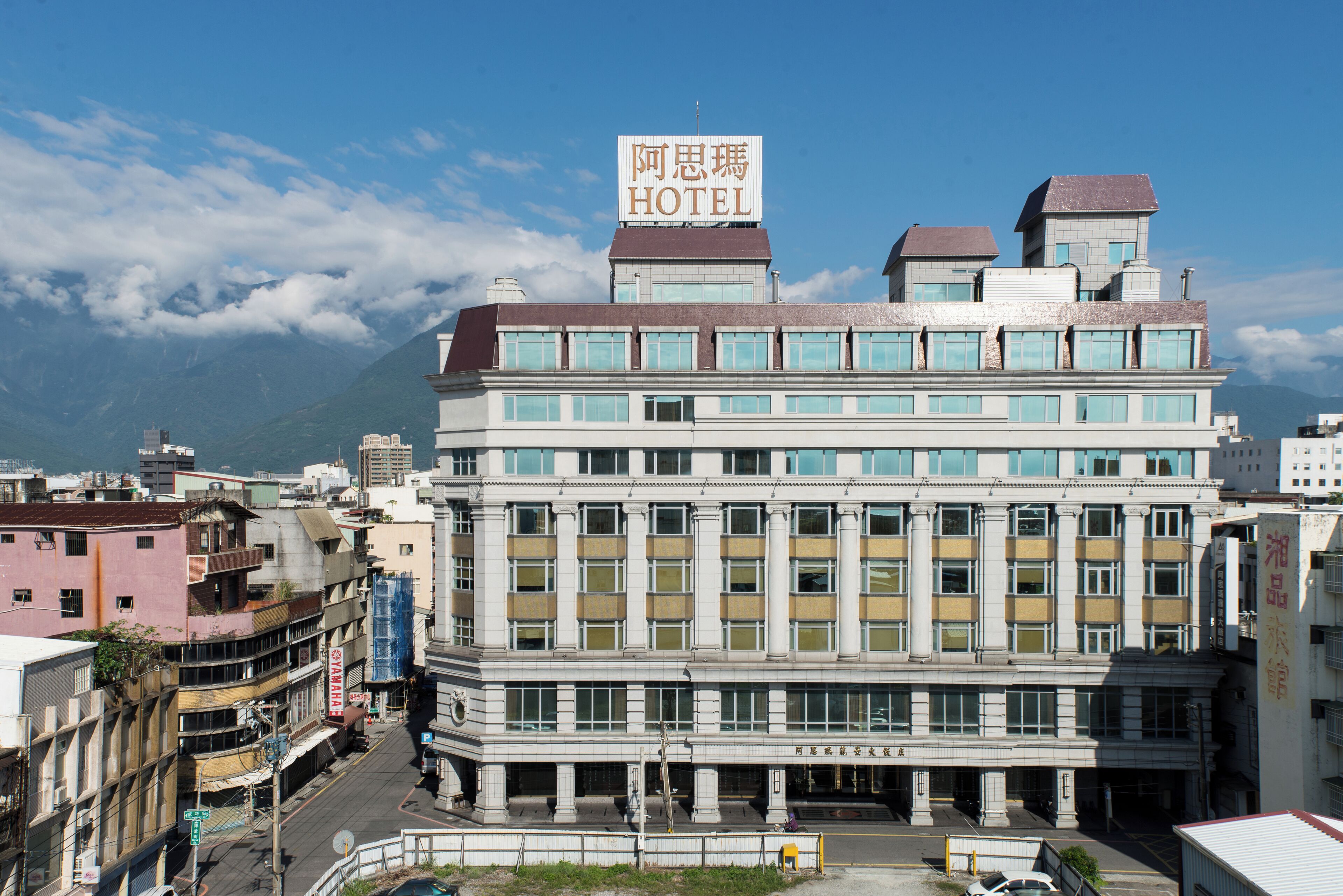 A hotel with a prominent sign, multiple floors, and a view of mountains in the background.