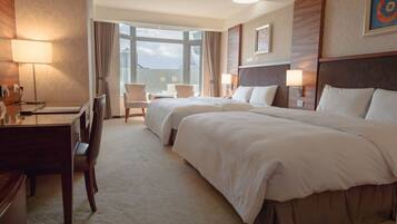 A hotel room with two beds, a desk, and a chair.