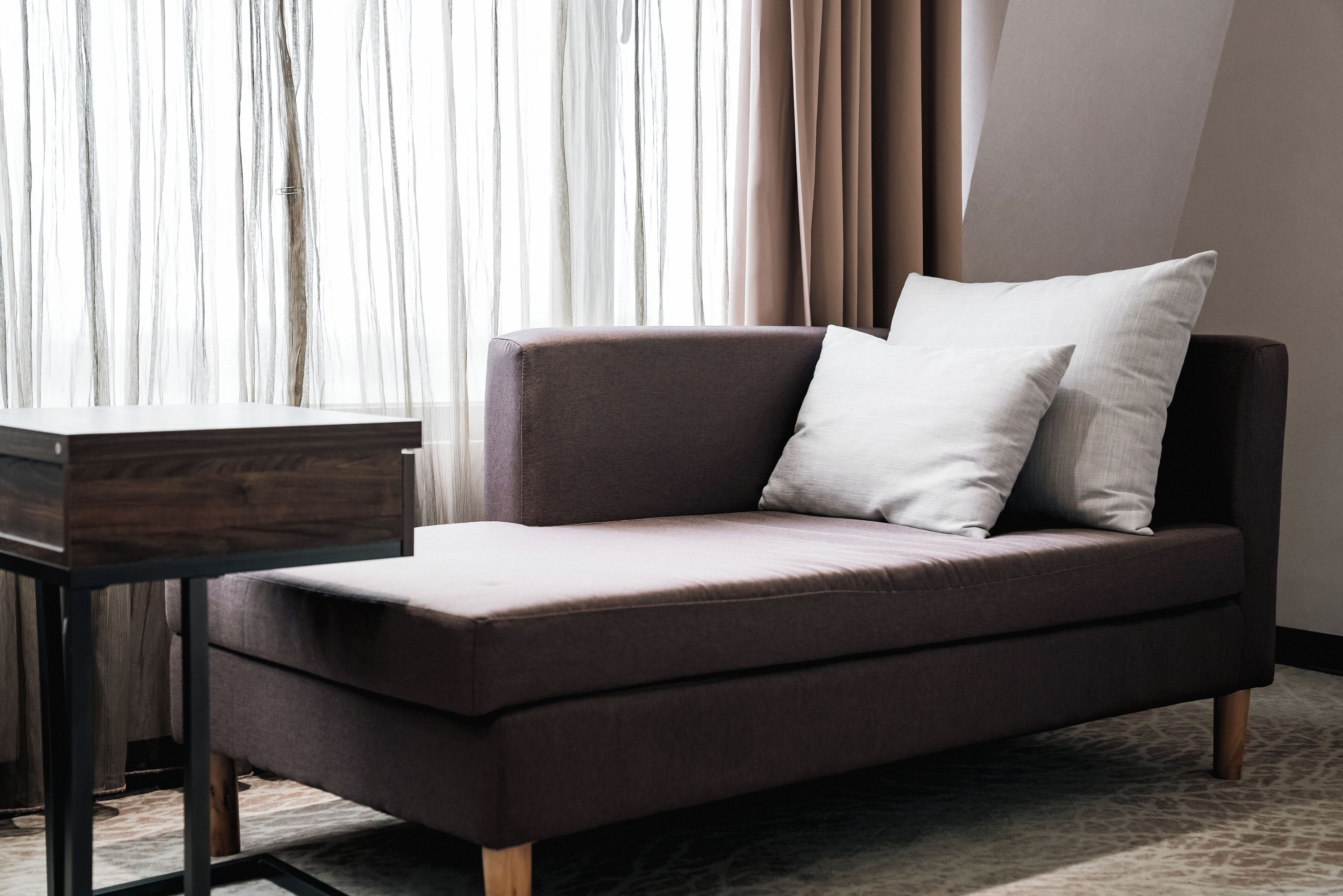 Una habitación moderna con un sofá, una mesita y una ventana con cortinas.