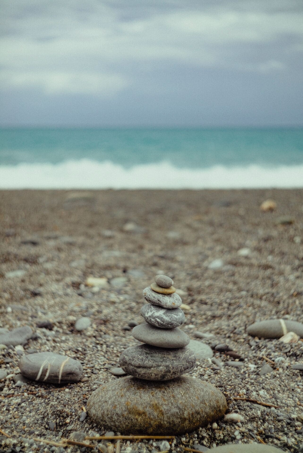 Una pila de piedras sobre una playa pedregosa con el océano al fondo.