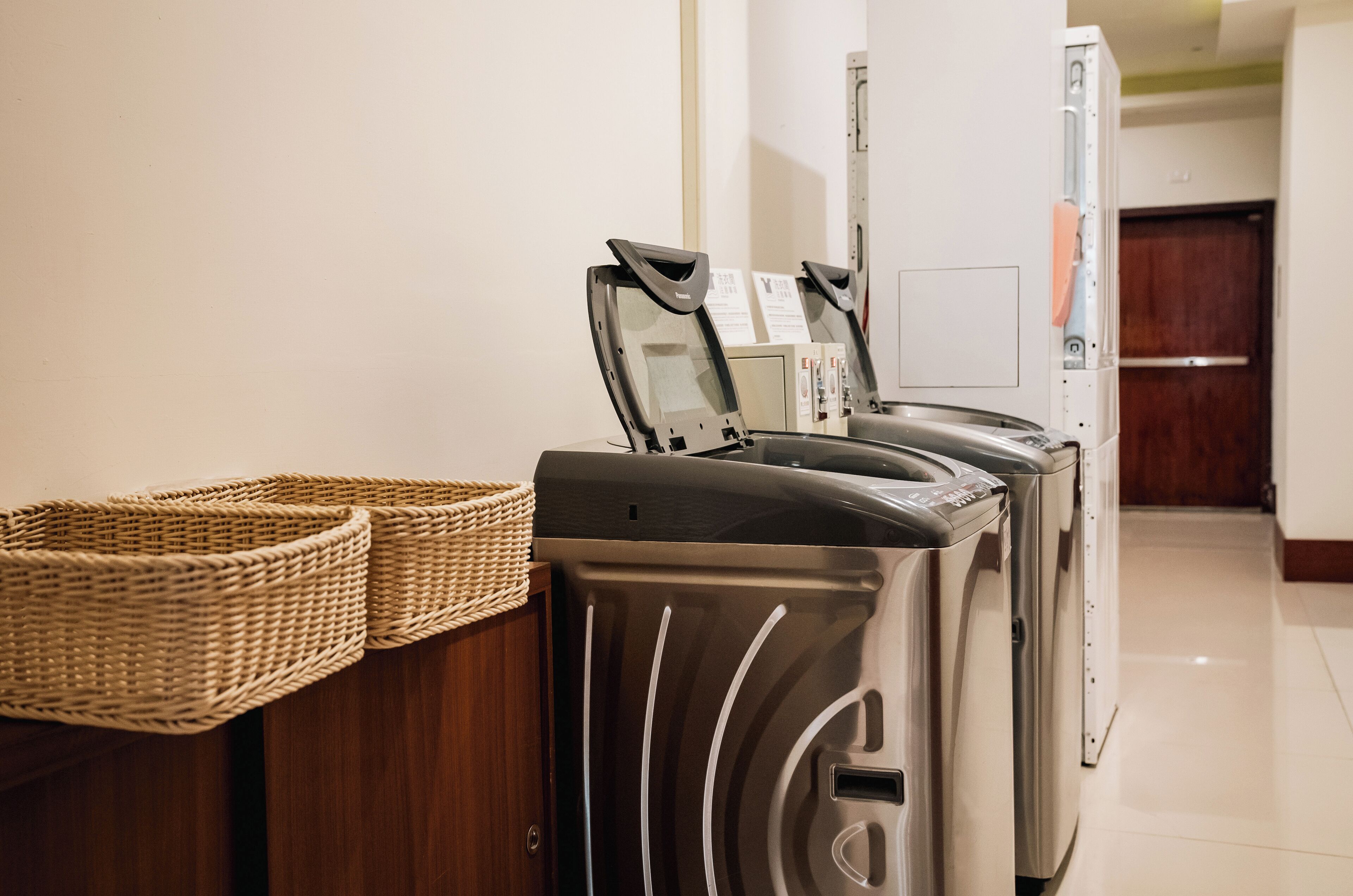 A laundry area with stacked washing machines and a wicker basket on a wooden counter.
