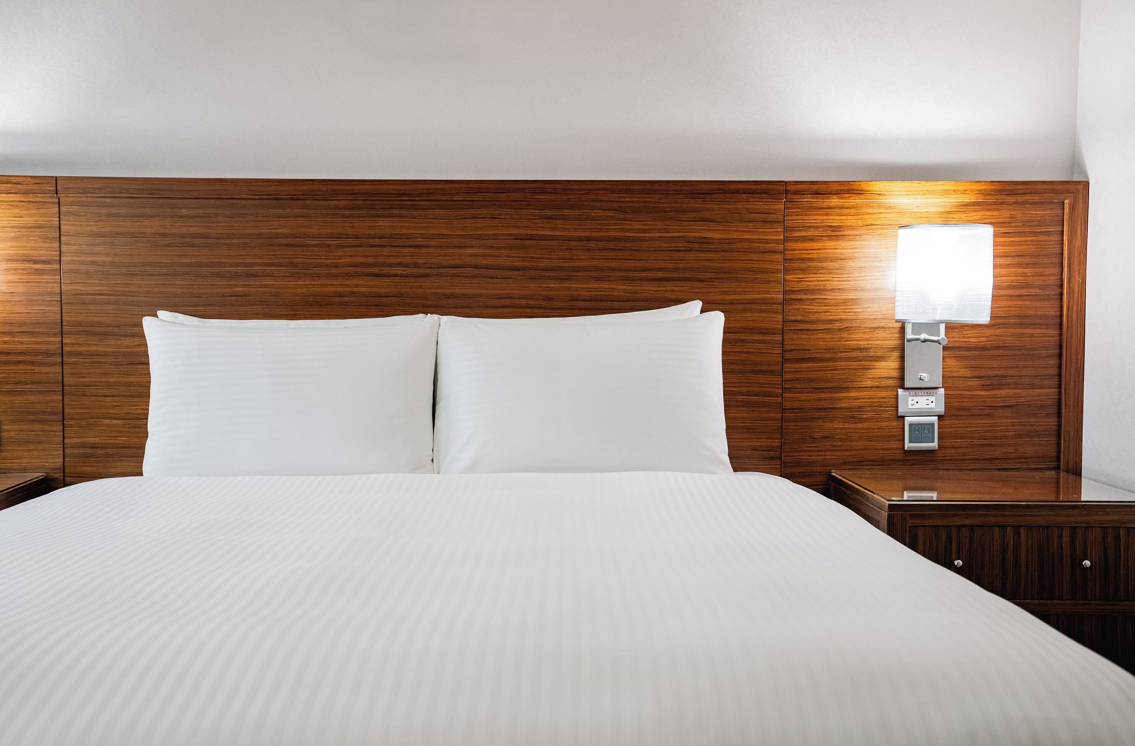 A neatly made bed with white linens in a hotel room.