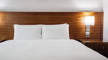 A neatly made bed with white linens in a hotel room.