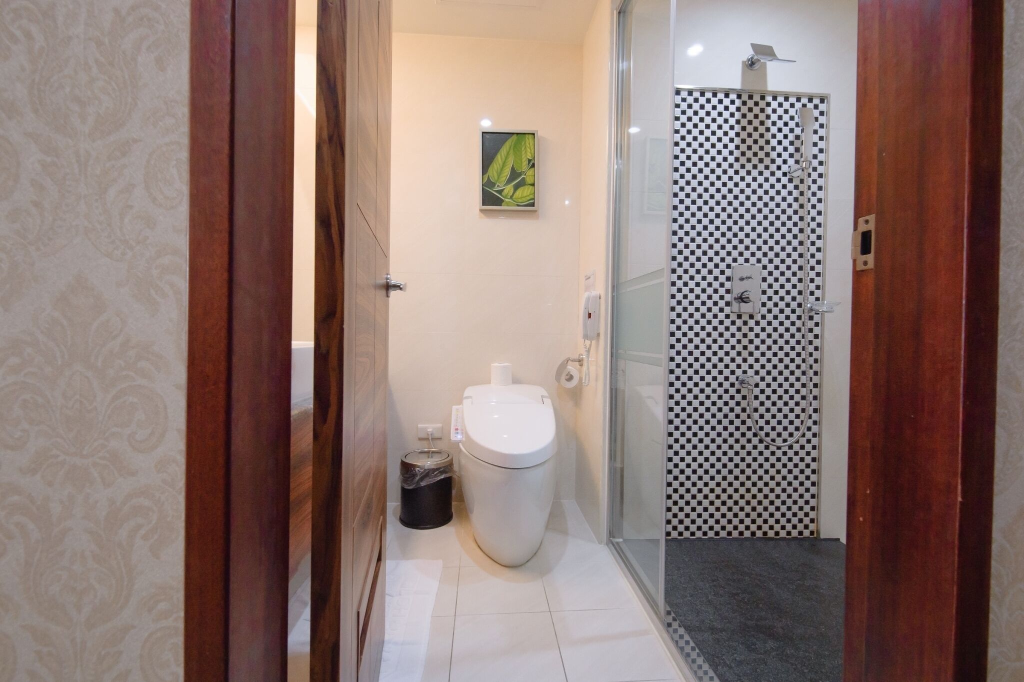 A bathroom with a toilet, a shower enclosure, and a trash bin.