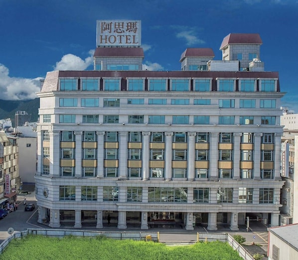 A multi-story hotel with a prominent sign, large windows, and a classical architectural style.