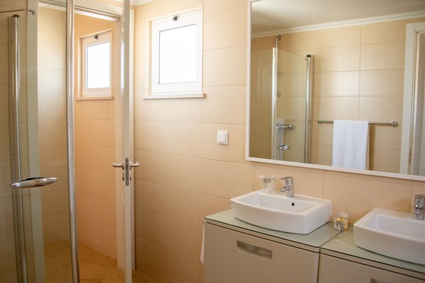 A bathroom with a glass shower enclosure, a white sink, and a large mirror. - Castro Marim Golf & Country Club (Castro Marim)