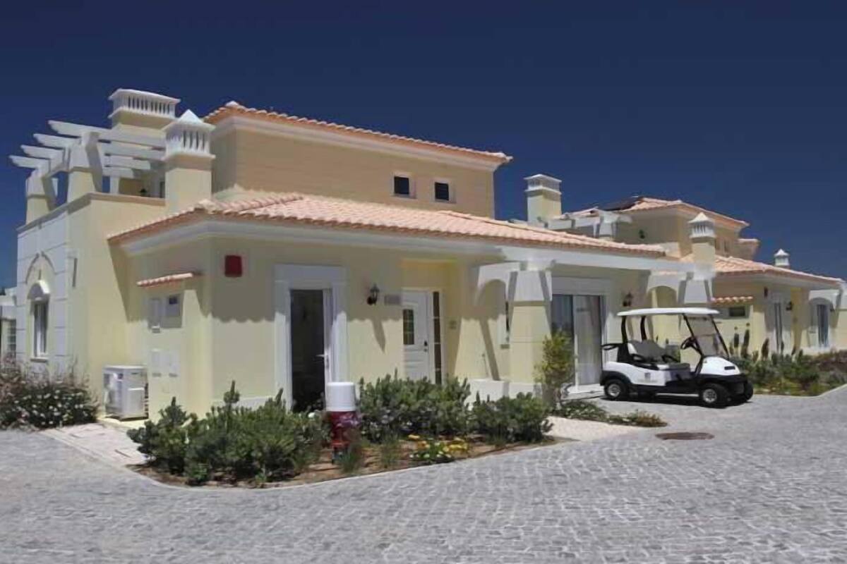 A two-story building with a tiled roof, a driveway, and a golf cart parked in front.