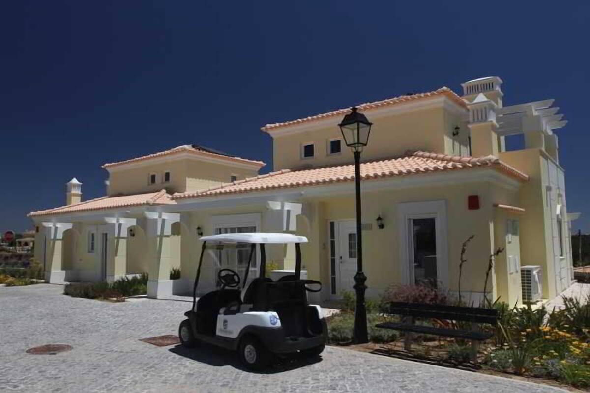 A building with a golf cart parked in front, a lamp post, and a bench.