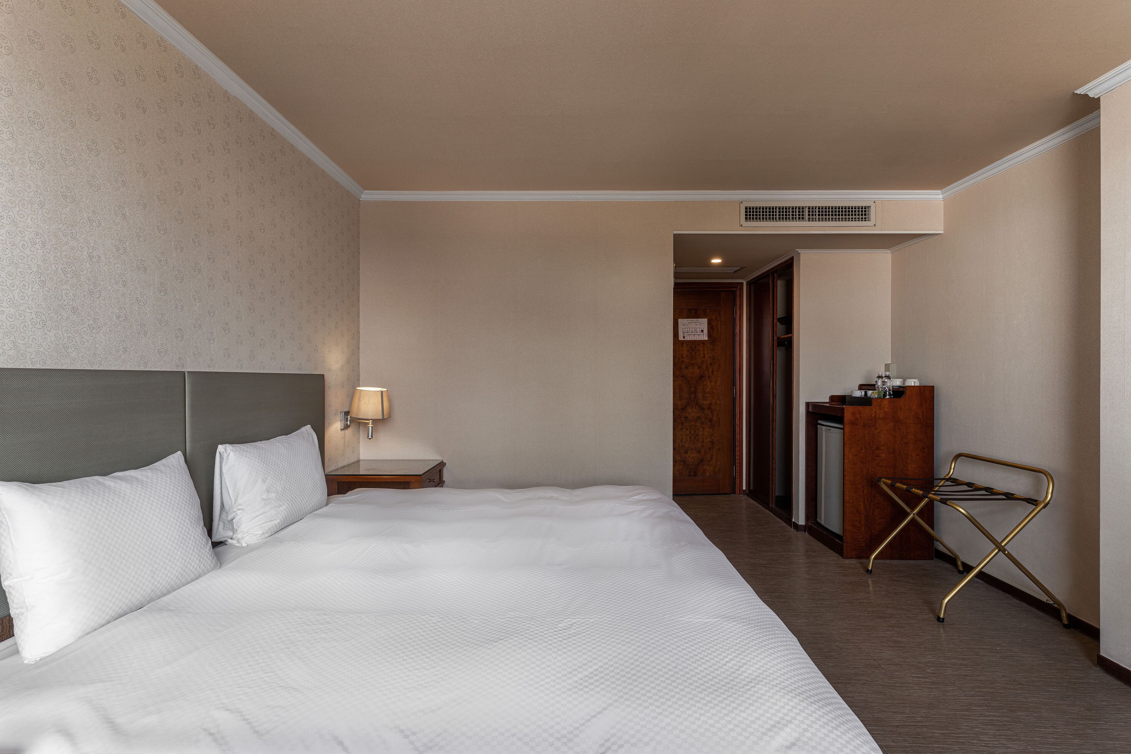 Una habitación de hotel con una cama grande, un escritorio con lámpara y un armario.