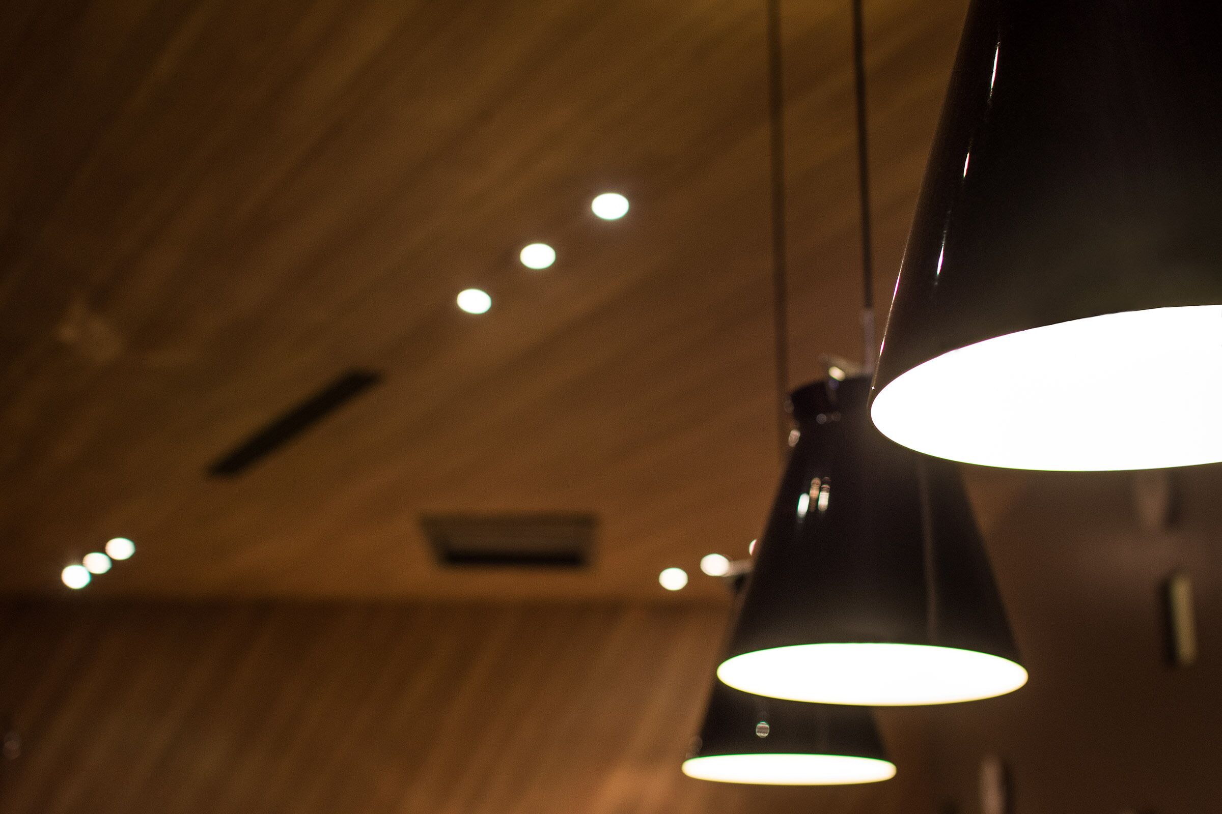 Hanglampen in een modern interieur met houten plafondpanelen.