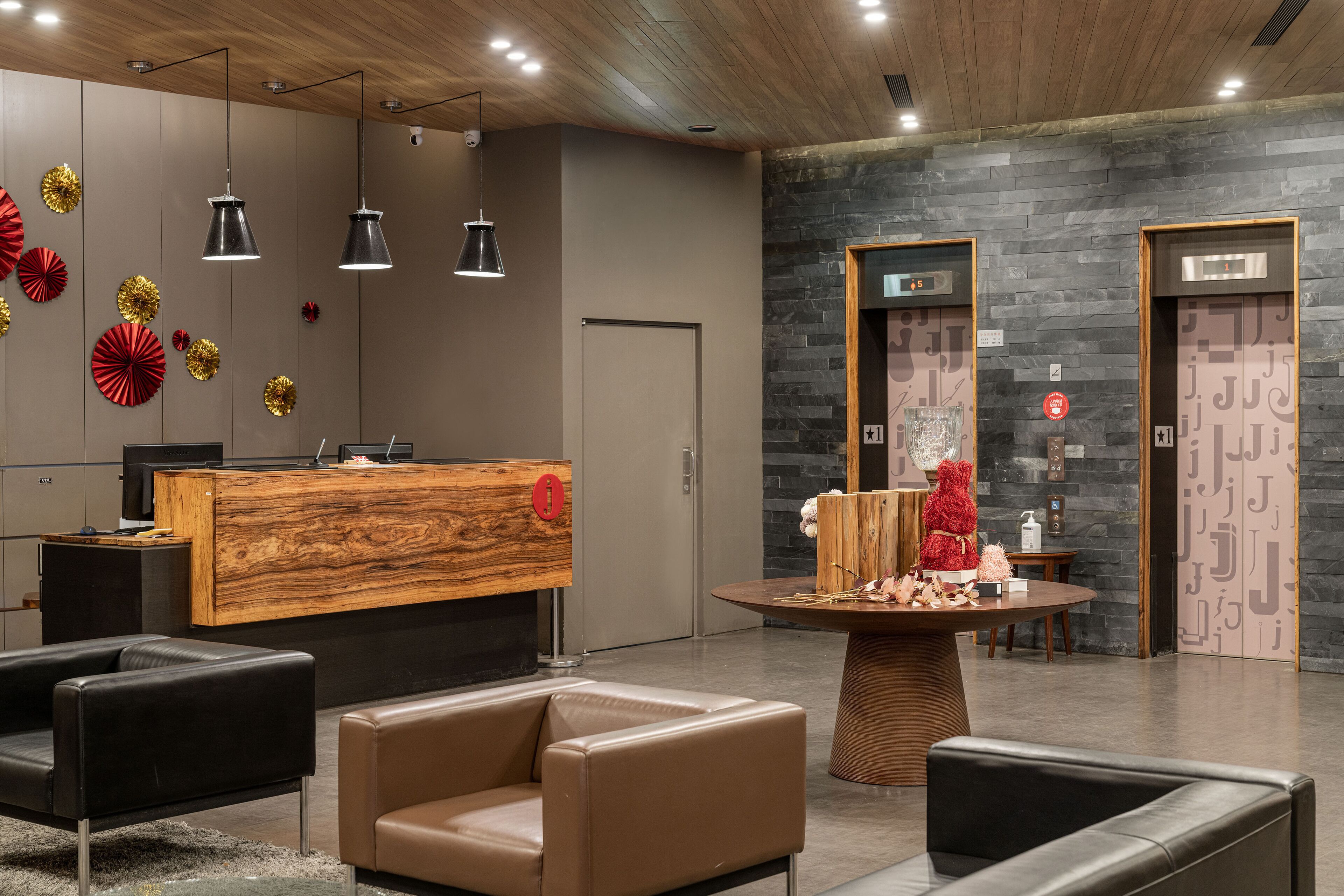 A modern reception area with a wooden reception desk, black leather sofas, and a decorative table.