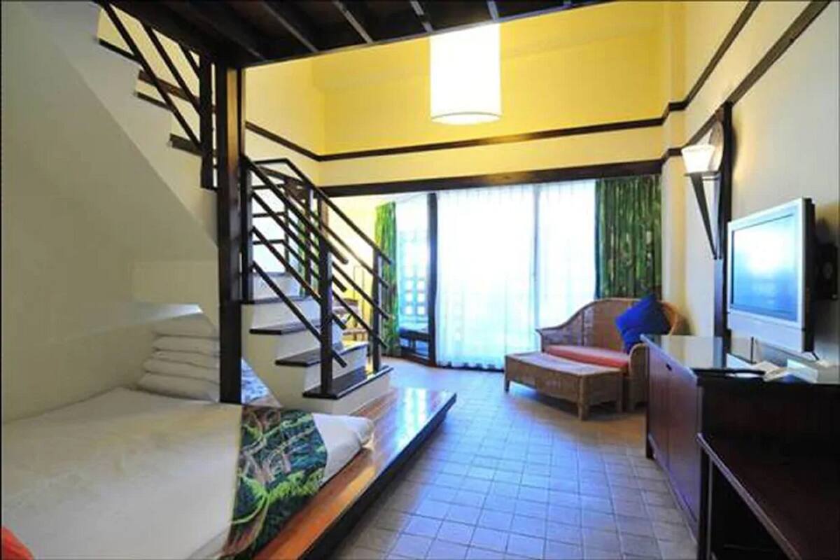 Una habitación con una cama, un sofá, un televisor y una escalera.