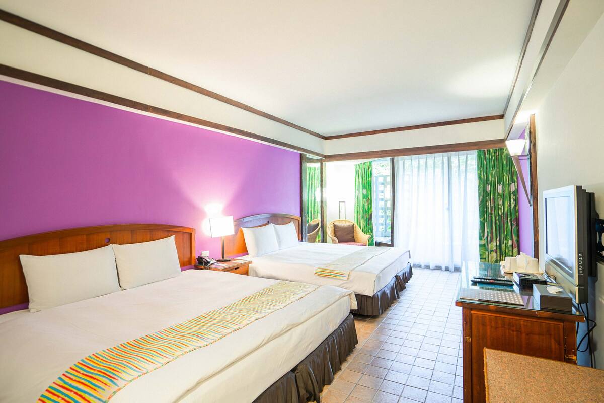 Una habitación de hotel con dos camas, un escritorio con computadora y televisor.