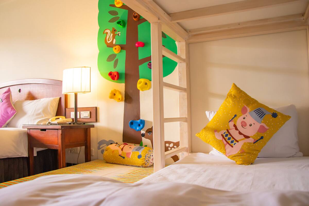 Habitación ideal para niños, con literas, pared de escalada y decoración lúdica.