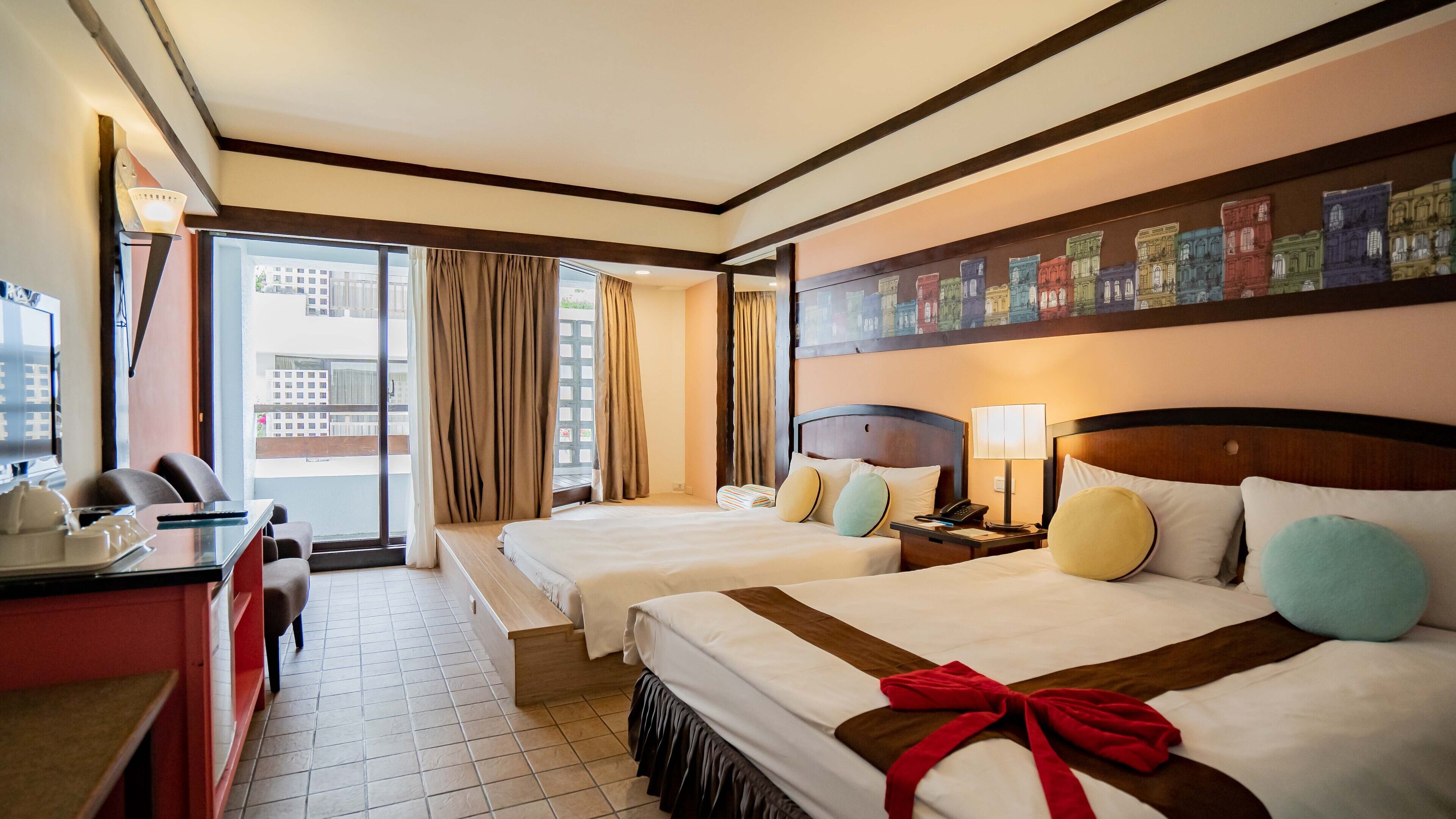 A hotel room with two beds, a desk, a chair, a TV, and a balcony with curtains.