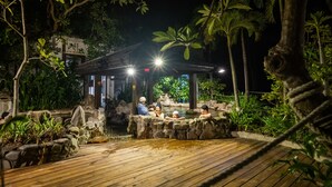 Eine Holzterrasse mit einem Steinelement für Wasser und einem Gazebo.