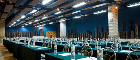 Une salle de conférence avec de longues tables, des chaises, des bouteilles d’eau et des plaques nominatives.