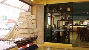 A model ship on display, a bar area with shelves of jars, and a patterned floor. - Grande Delmon (Panaji)