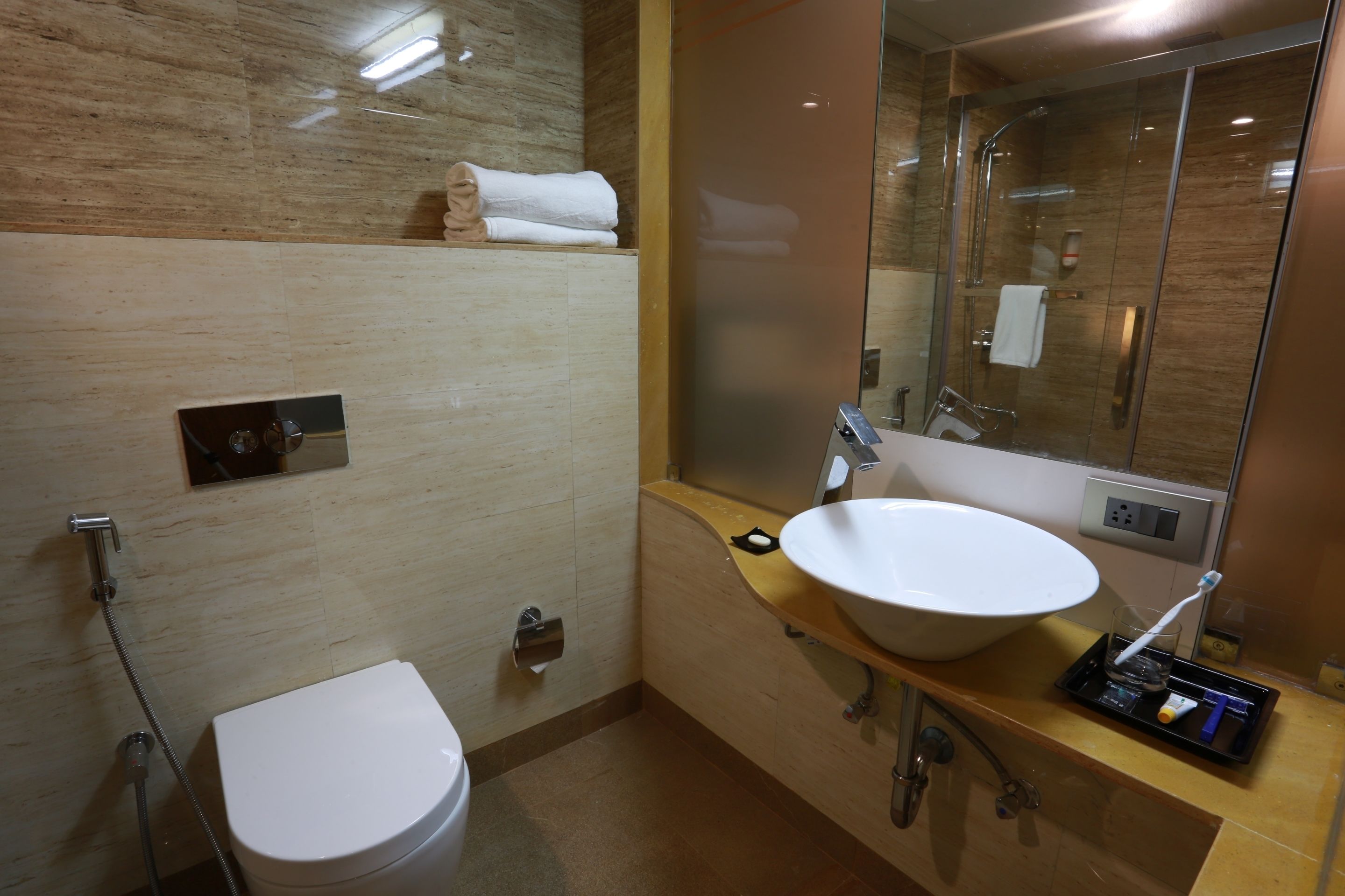 Een moderne badkamer met een wit toilet, een ruime wastafel en een douche met glazen wanden.