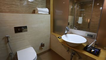 Een moderne badkamer met een wit toilet, een ruime wastafel en een douche met glazen wanden.