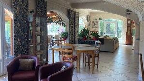 A spacious lobby with a high ceiling, a dining area, and a seating area with armchairs and a sofa. - Les Belles Terrasses (Tourrettes-sur-Loup)