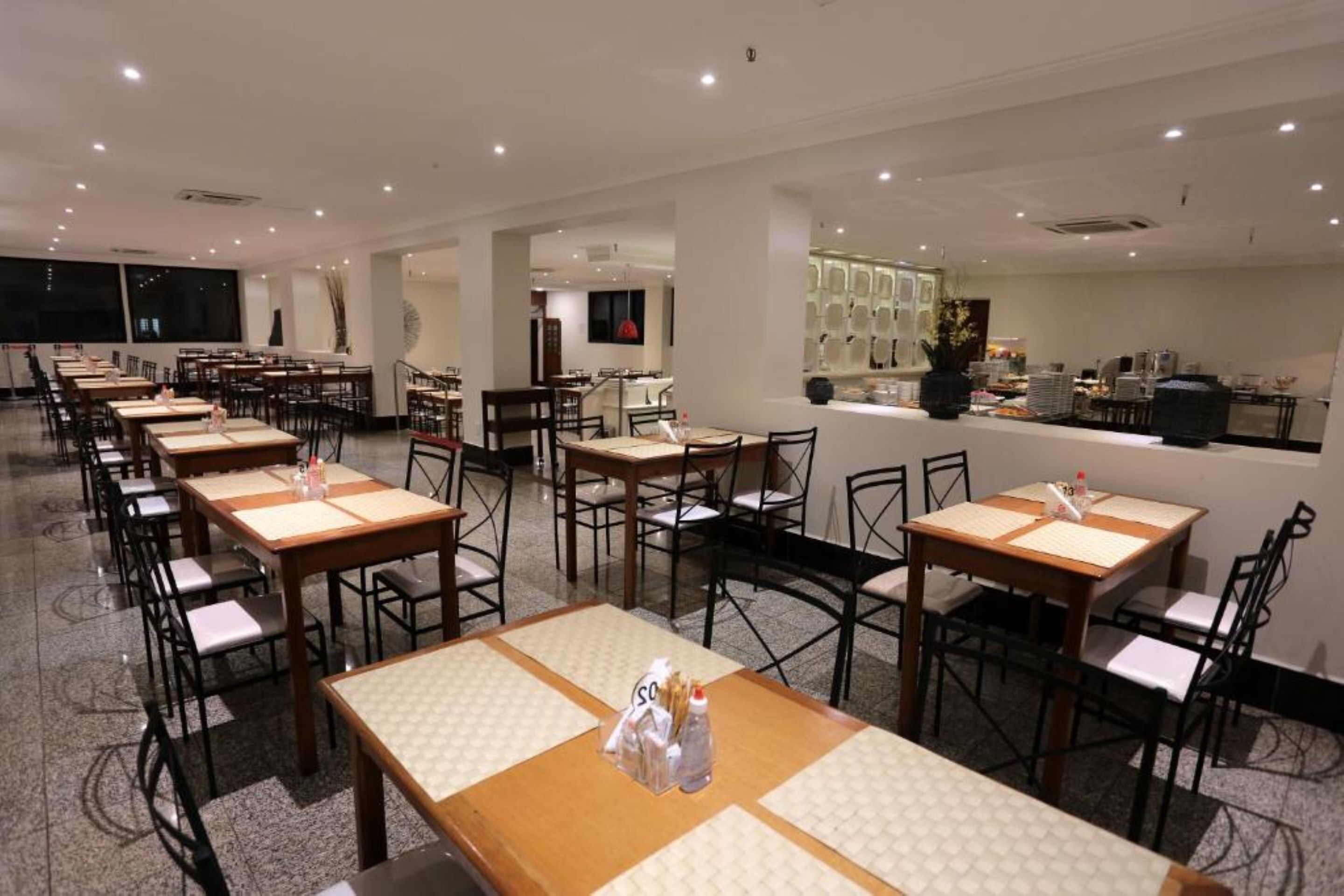 A spacious dining area with multiple tables and chairs, a counter with food items, and a modern interior design.