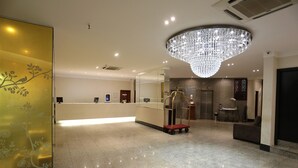 A hotel reception area with a modern chandelier, a reception desk, and a seating area. - Taiwan Hotel (Ribeirão Preto)