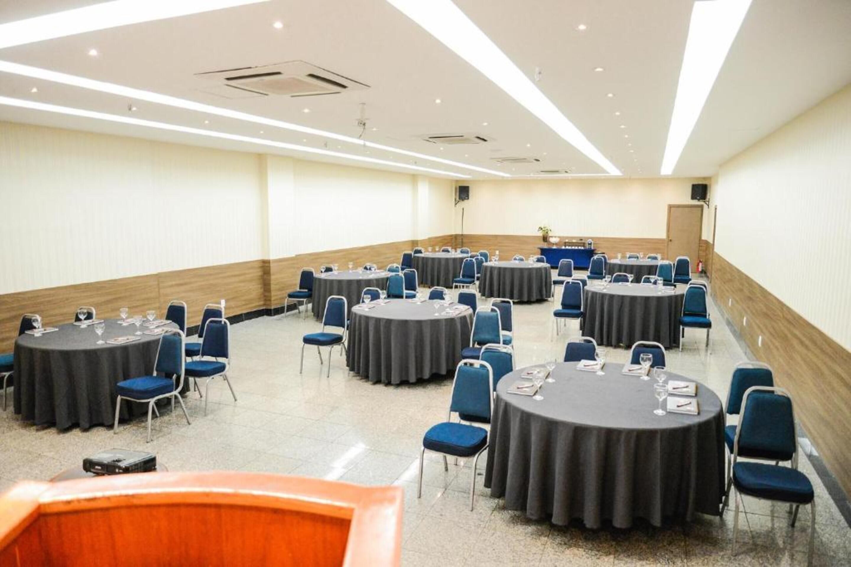 A conference room with multiple round tables, each with chairs and table settings.