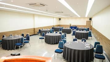 A conference room with multiple round tables, each with chairs and table settings.