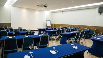 A conference room with multiple tables and chairs, equipped with nameplates and wine glasses.