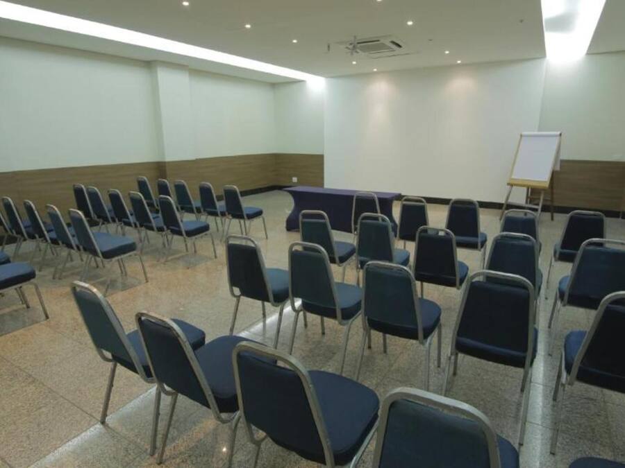 Een vergaderzaal met rijen stoelen, een whiteboard en een beamer.
