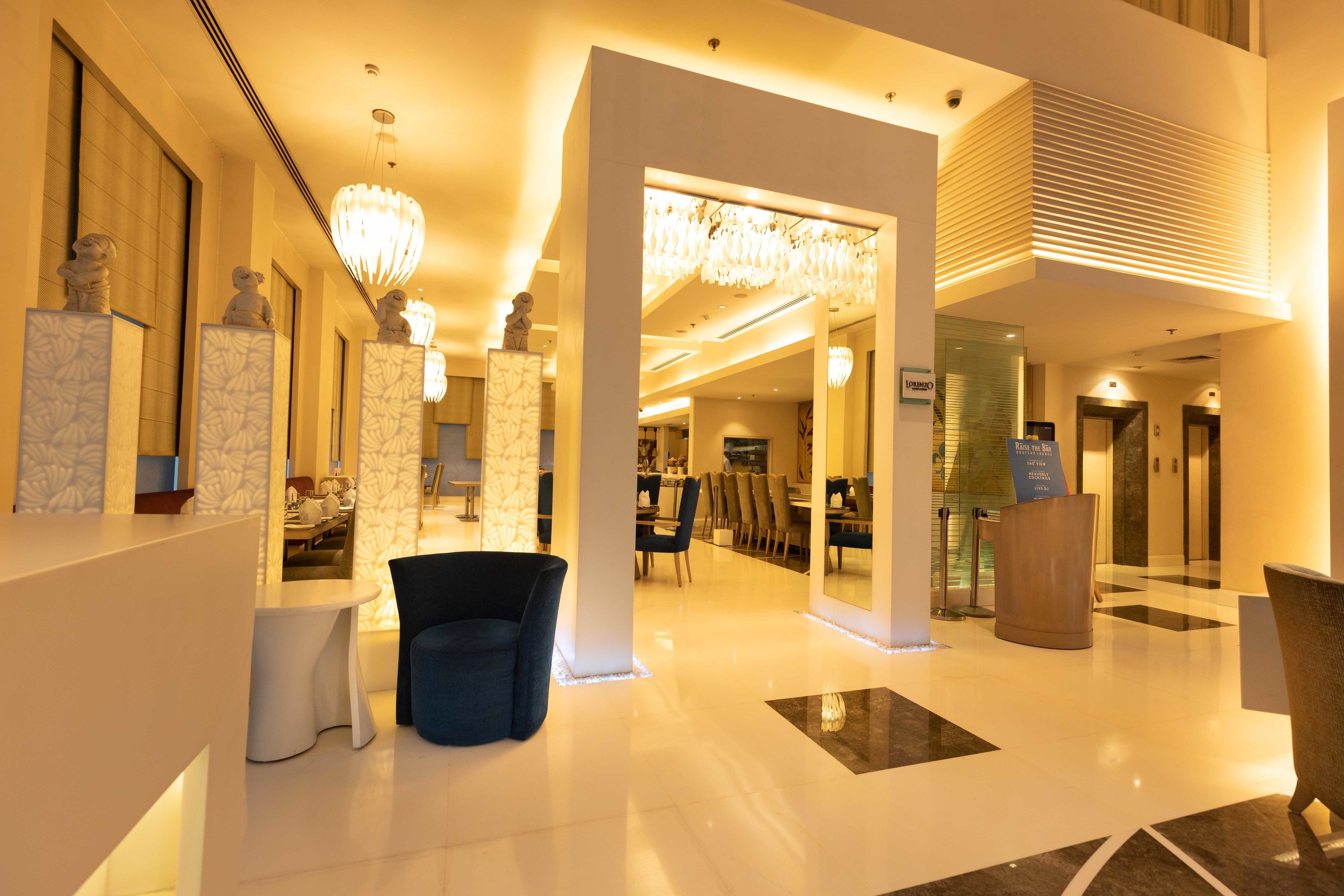 A spacious lobby with a modern design, featuring a reception desk, seating area, and a dining space.