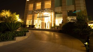 Un hotel con un cartel llamativo en la parte superior, una entrada bien iluminada y un camino pavimentado que conduce a la entrada.