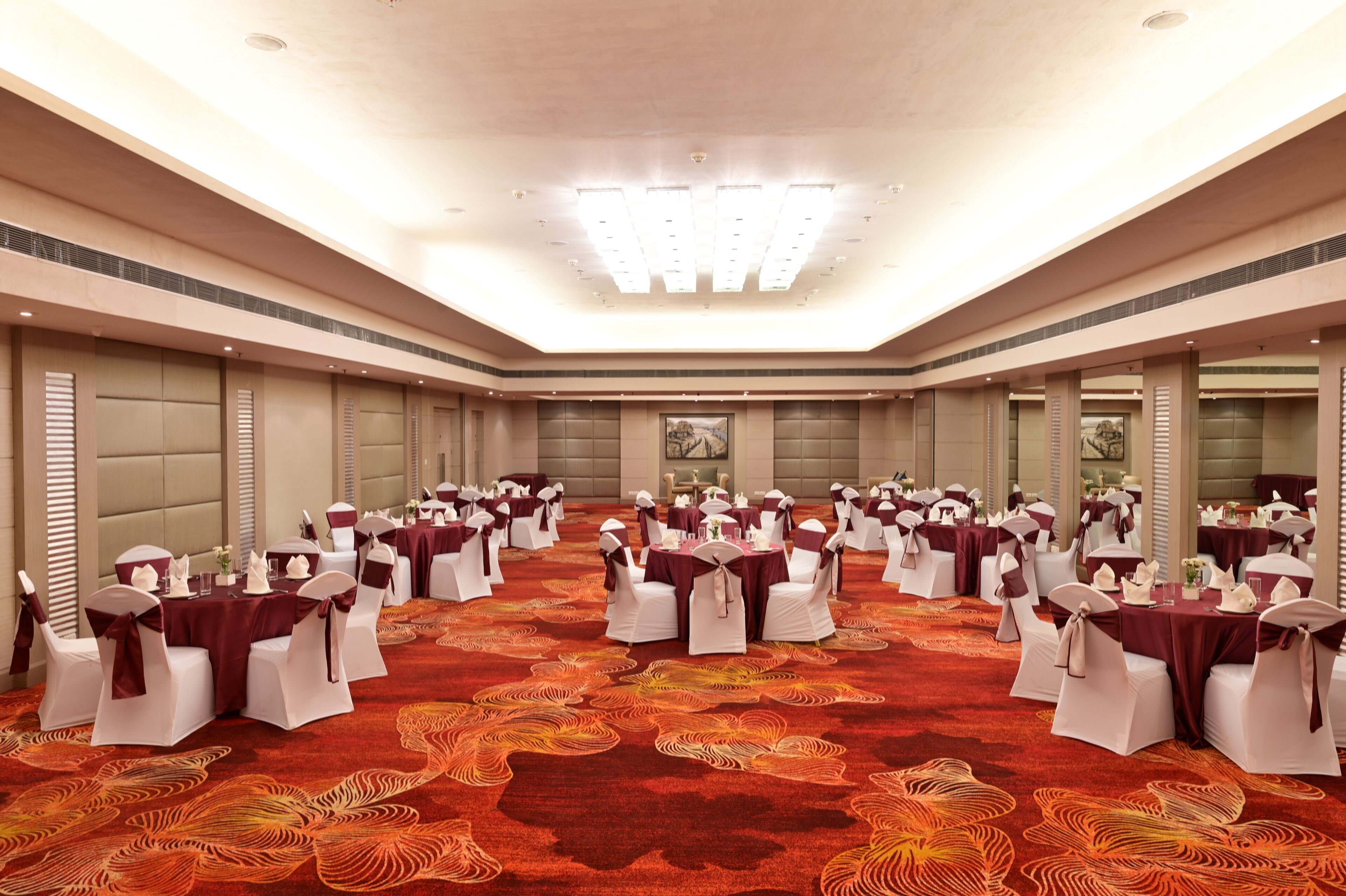 A large conference room with round tables and white chairs, arranged in a U-shape.